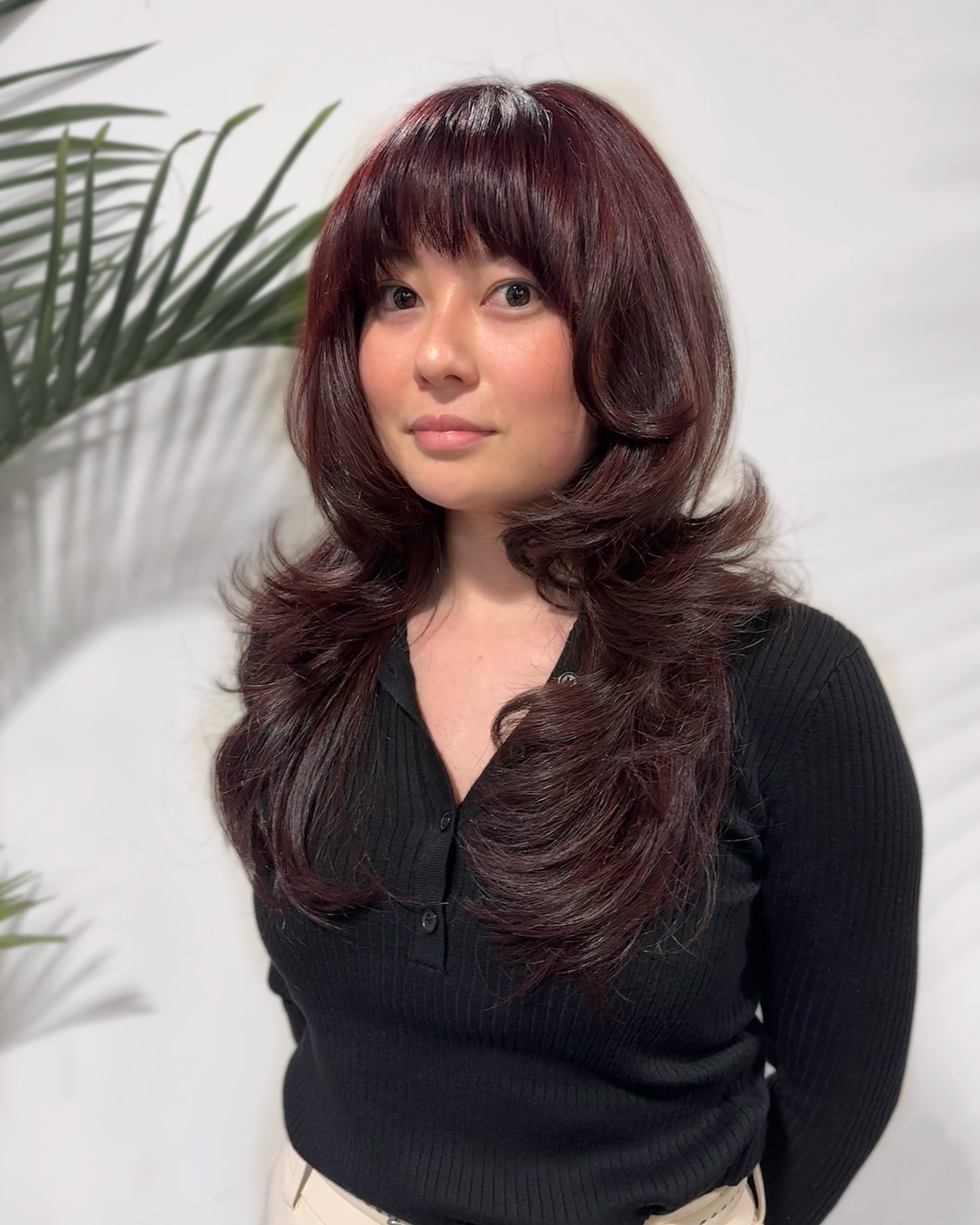 Rich Burgundy Layered Waves with Side-Swept Bangs