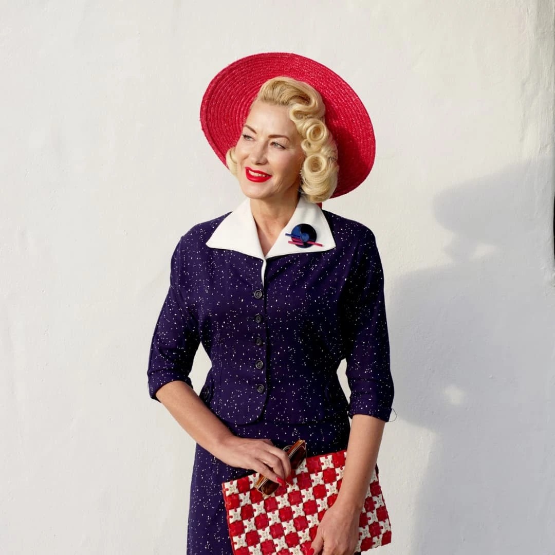 Bright Blonde Sculpted Curls with Red Hat Accent