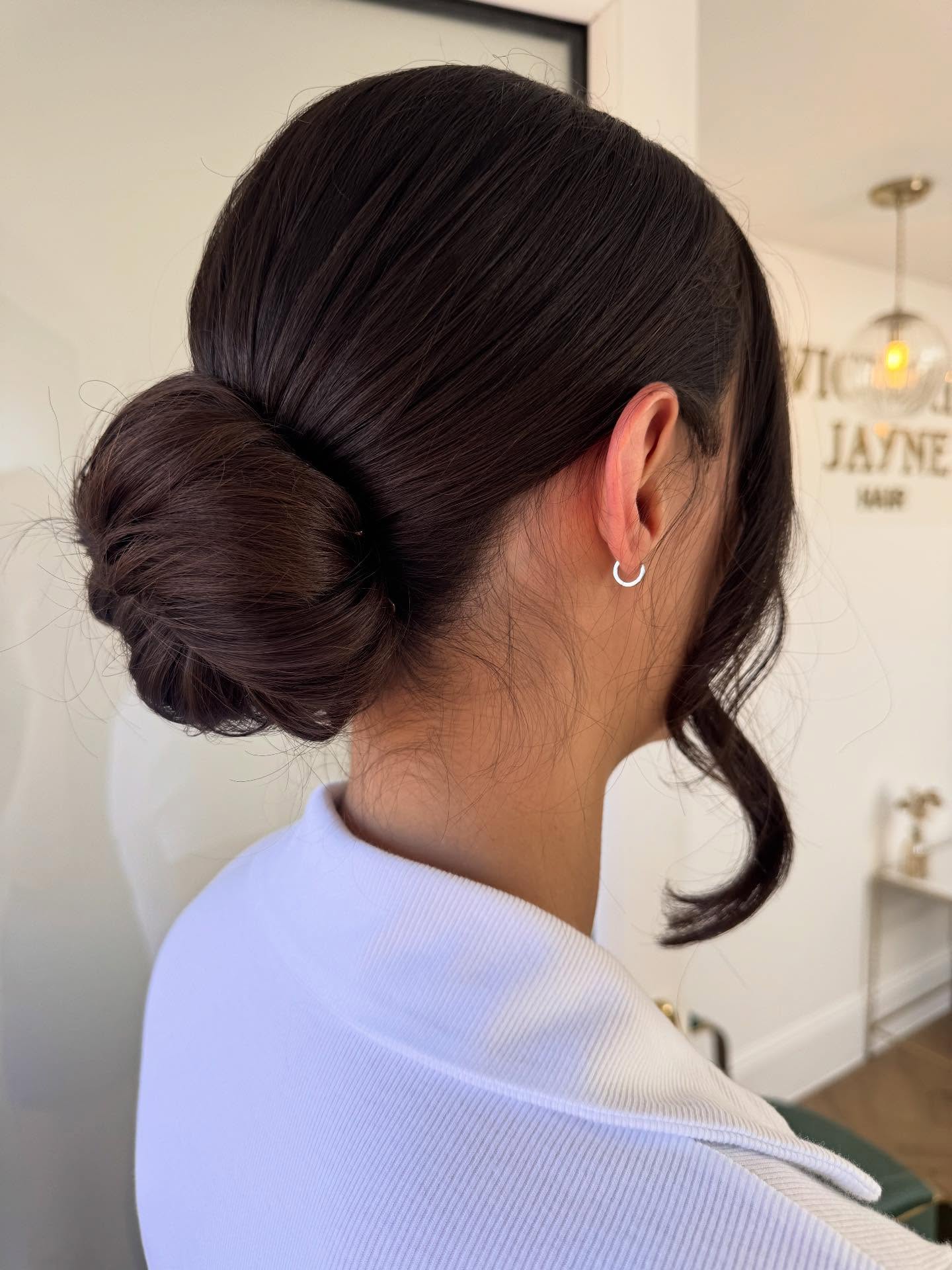 Sleek Side-Swept Low Chignon with Whimsical Curl