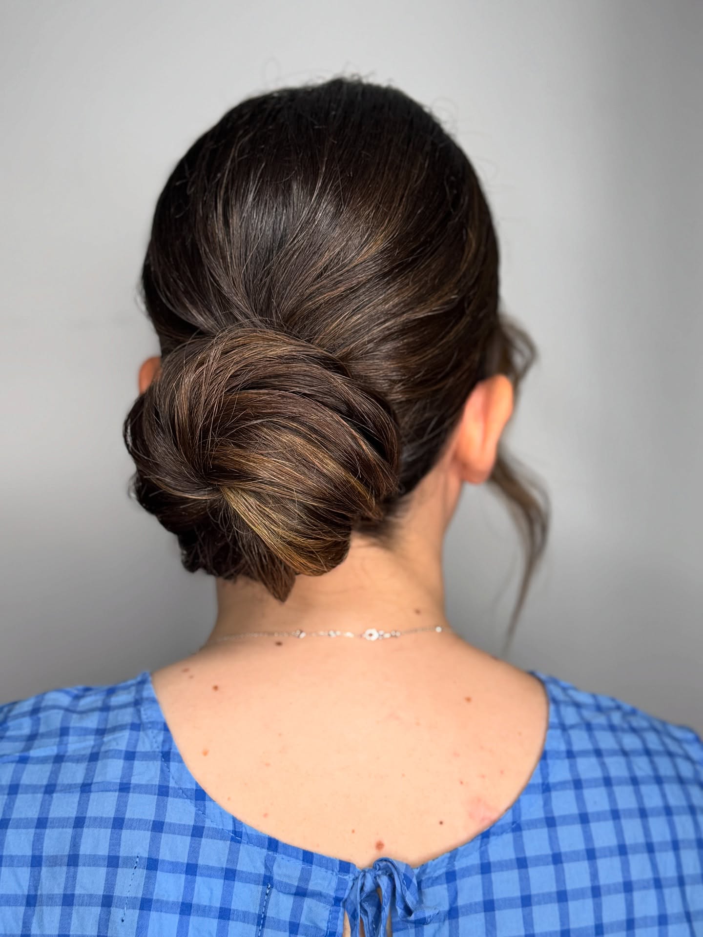 Low Twisted Chignon with Petal-Fold and Subtle Caramel Accents