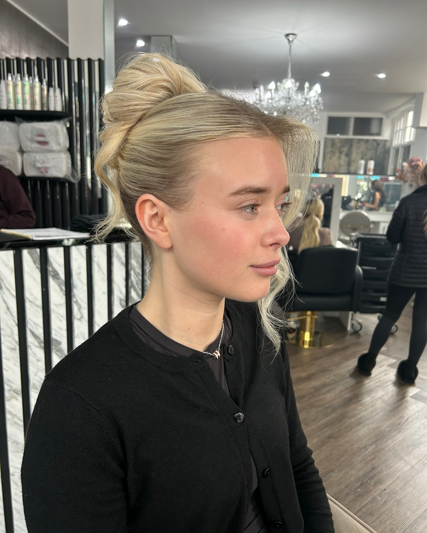 Polished High Teased Bun with Face‑Framing Tendril and Root Shadow