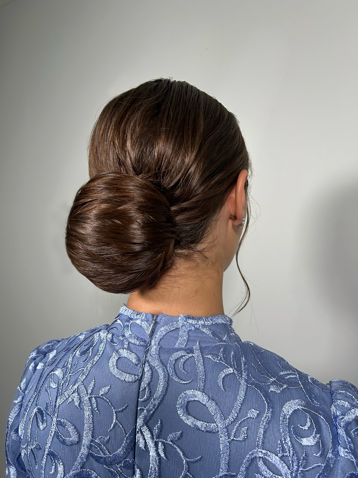 Polished Low Spiral Chignon with Subtle Face‑Framing Tendril