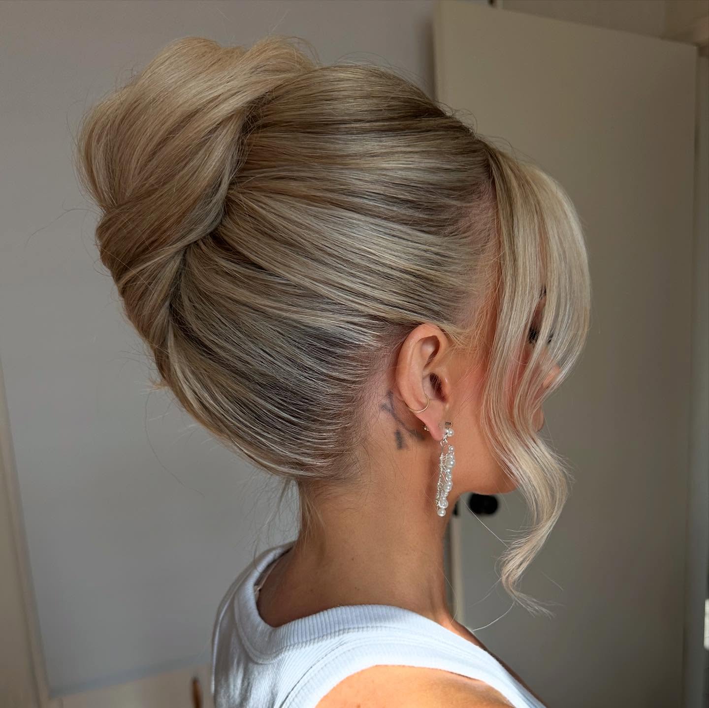 Sleek Twisted High French Knot with Face‑Framing Tendrils