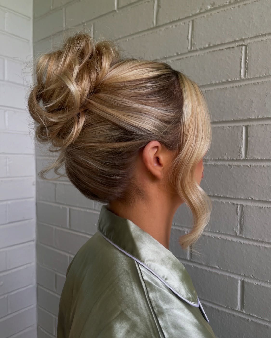 Soft Bronde High Bun with Folded Sections and Face-Framing Tendril