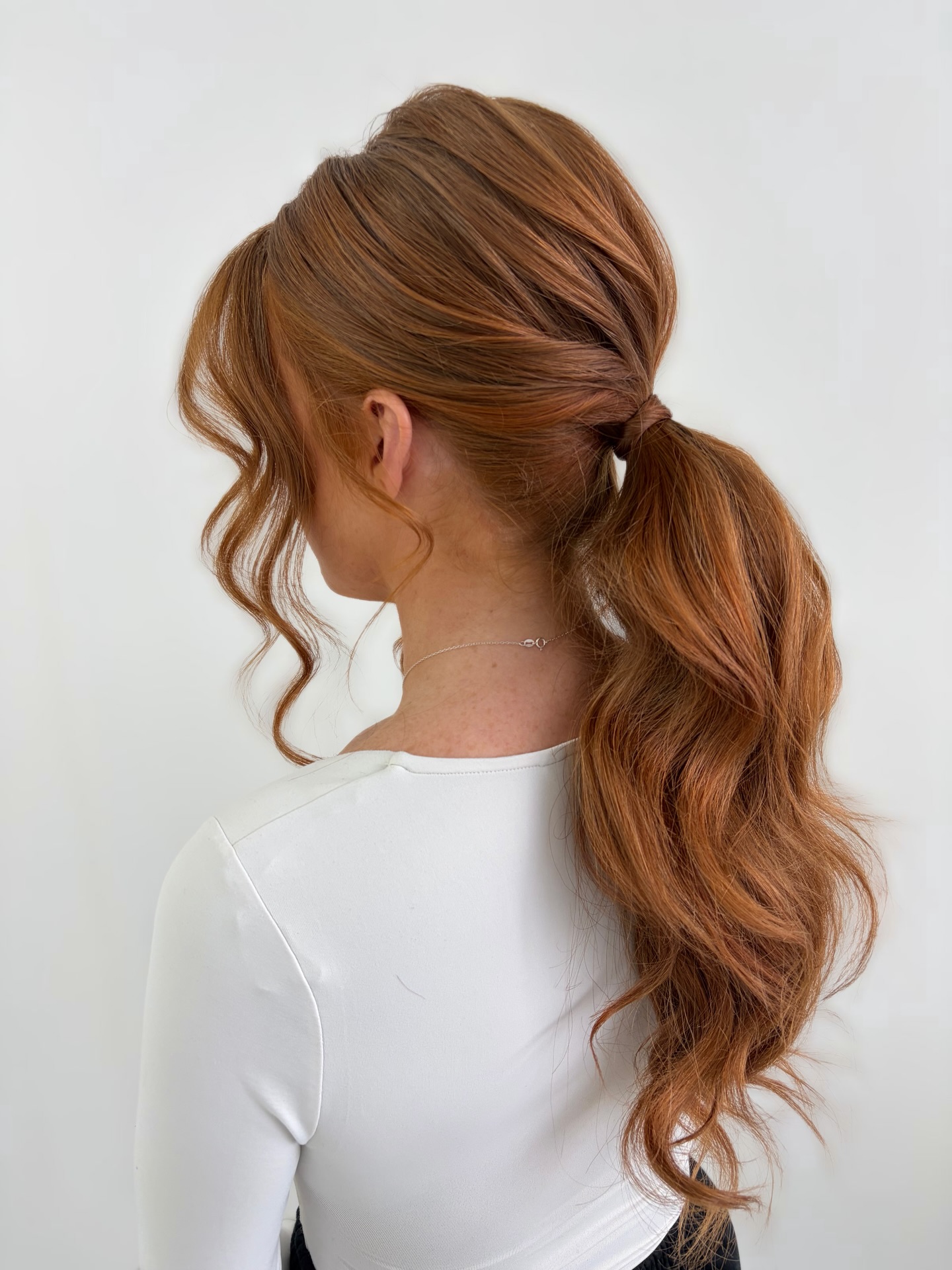 Voluminous Copper Low Pony with Wrapped Base and Face-Framing Tendrils