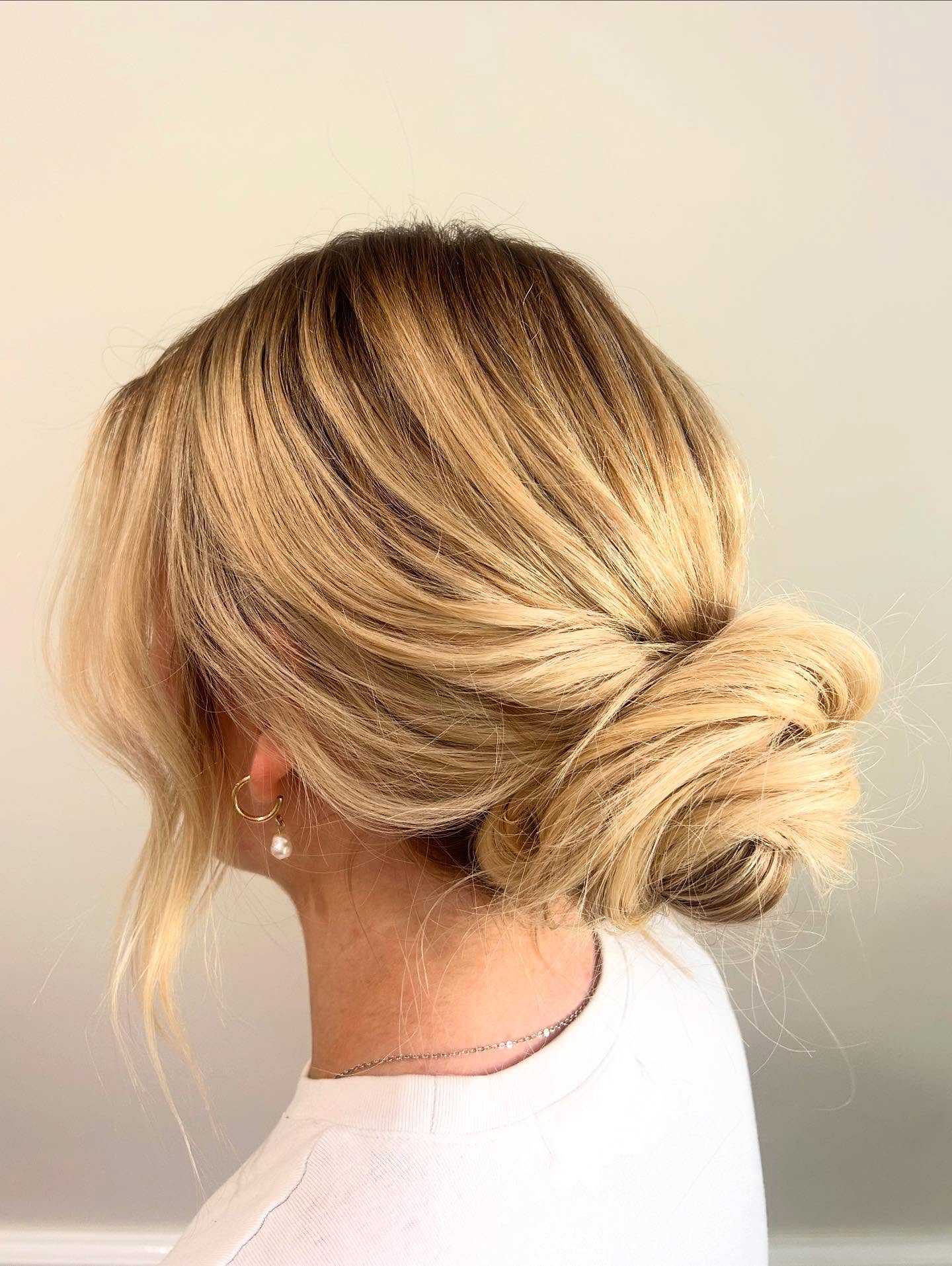 Low Twisted Blonde Balayage Bun with Face-Framing Tendrils