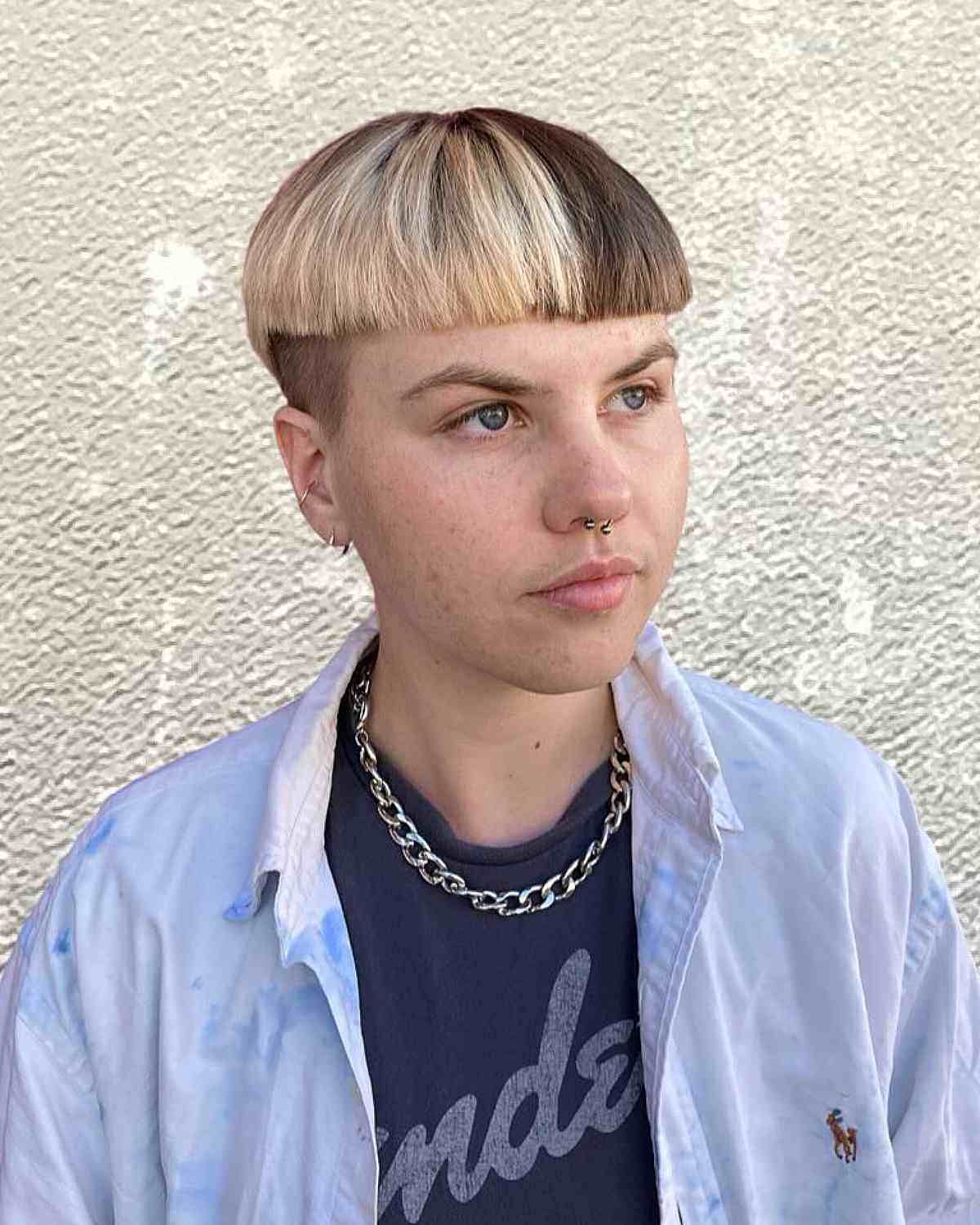 Two-tone bowl cut with platinum blonde and dark brown hair, featuring a gender neutral undercut