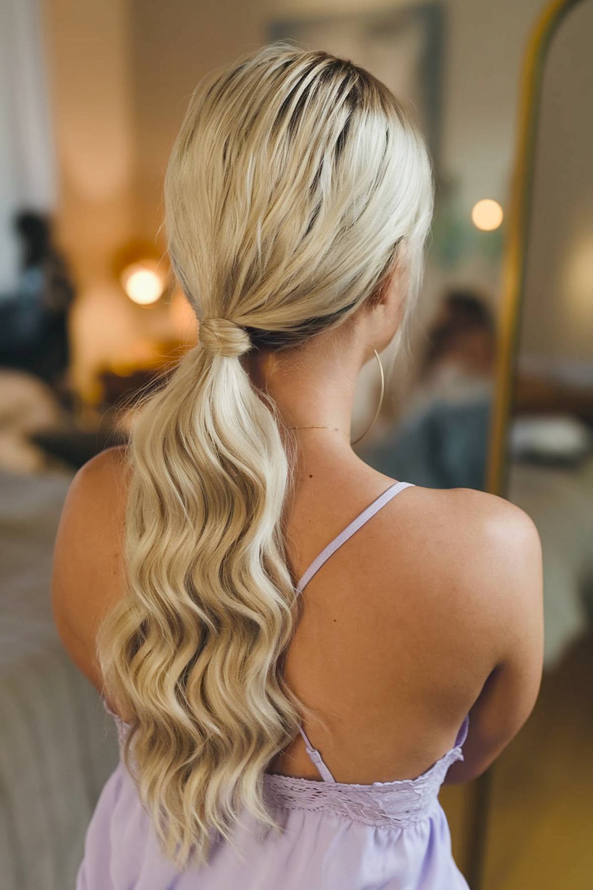 Chic low ponytail with soft waves and a wrapped hair tie, blending casual elegance with glamour