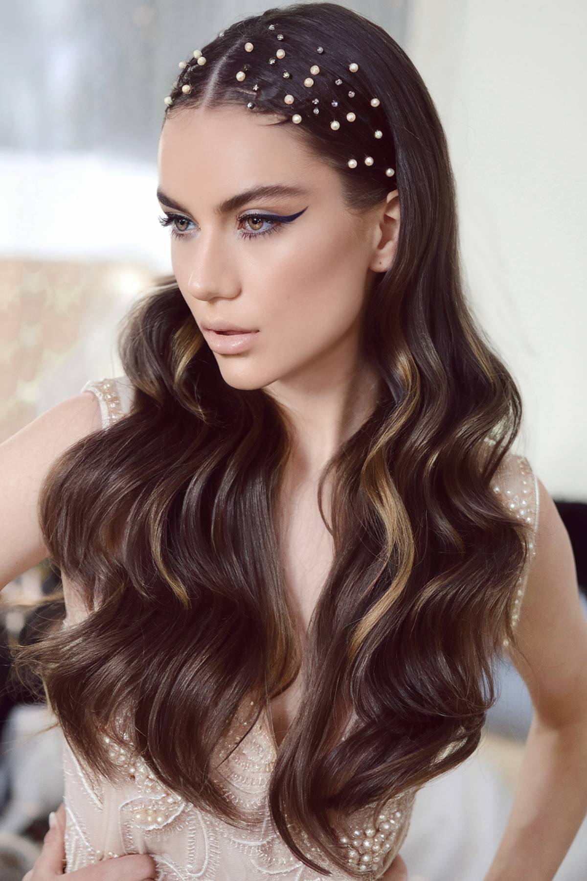 Luxe, voluminous waves with pearl-studded parting for a statement glam party hairstyle