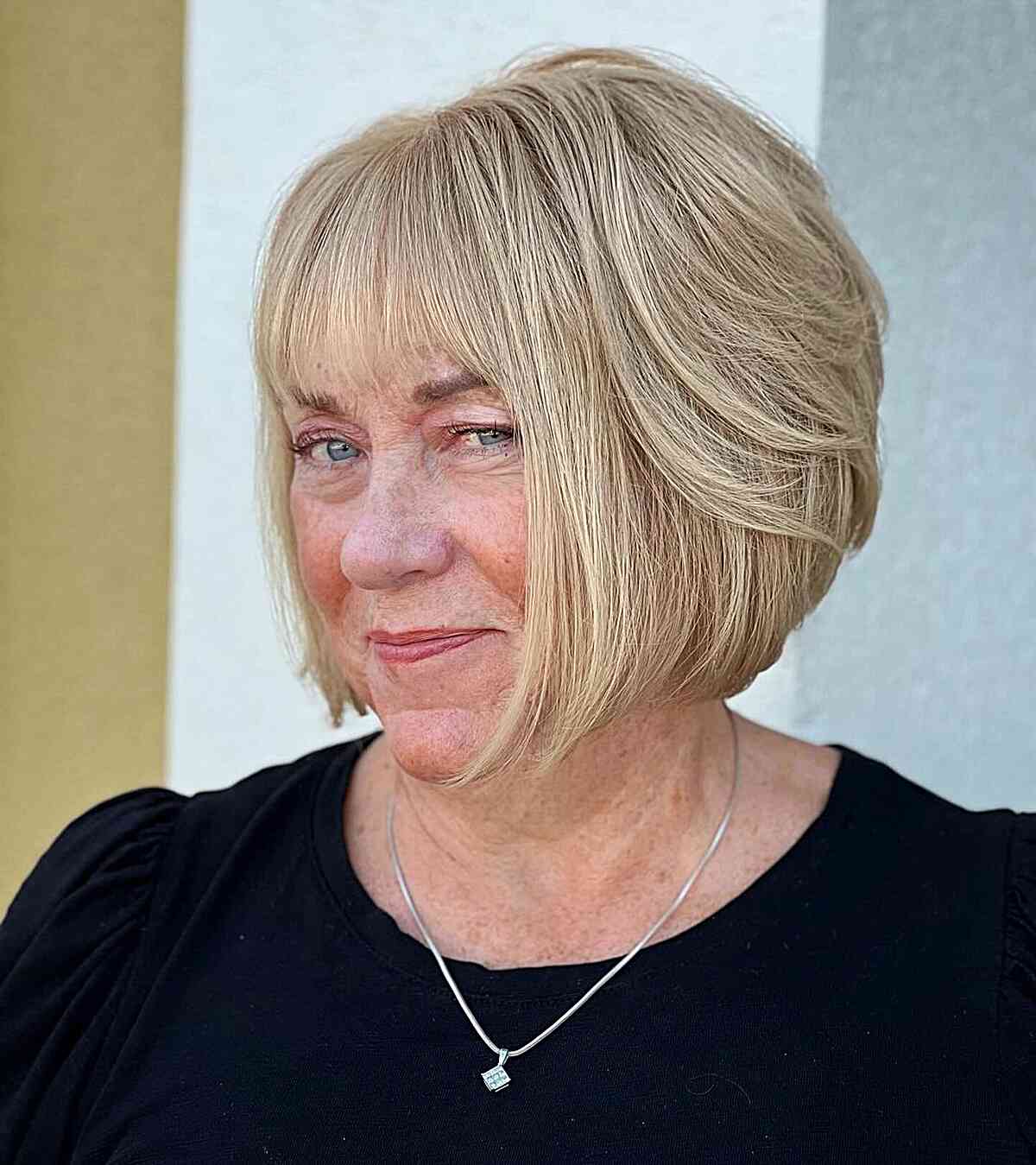Chin-Grazing Graduated Blonde Bob with Light Bangs for Ladies Over Fifty with Rounded Faces