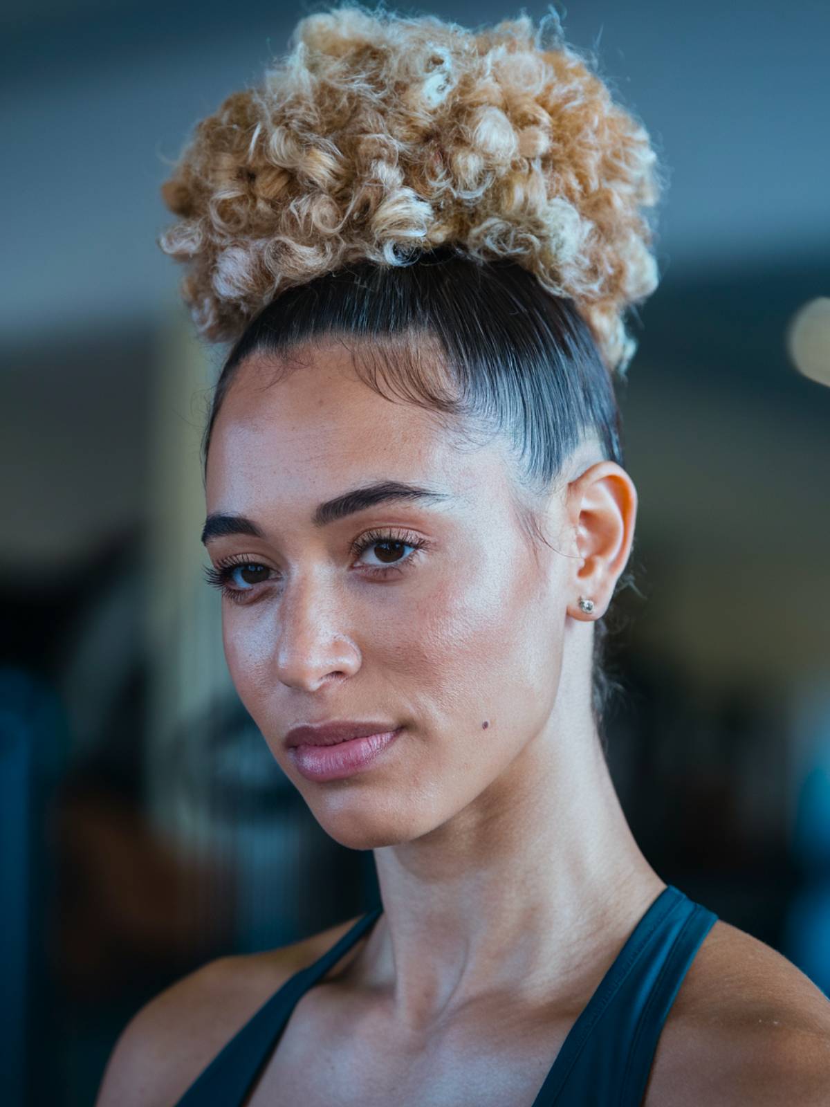 High curly bun with tight coils and slicked edges for an active, gym-ready look