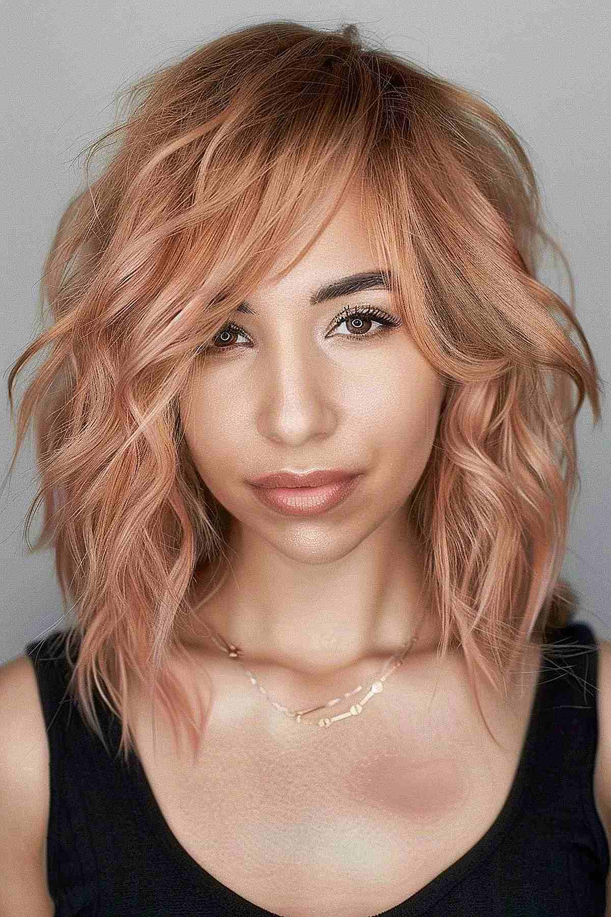 Medium-length hairstyle with layers and dusty peach waves, ideal for adding volume and softness to the hair, suitable for a variety of skin tones.