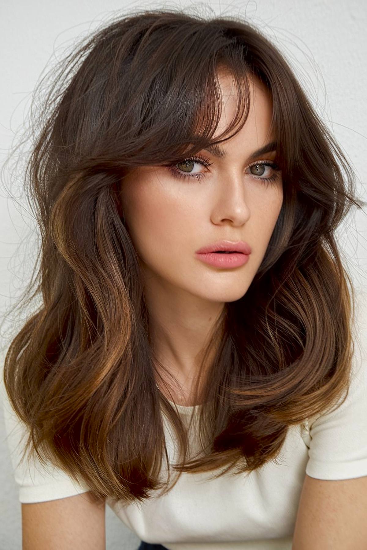 Medium-length wavy hairstyle with curtain bangs for thick hair