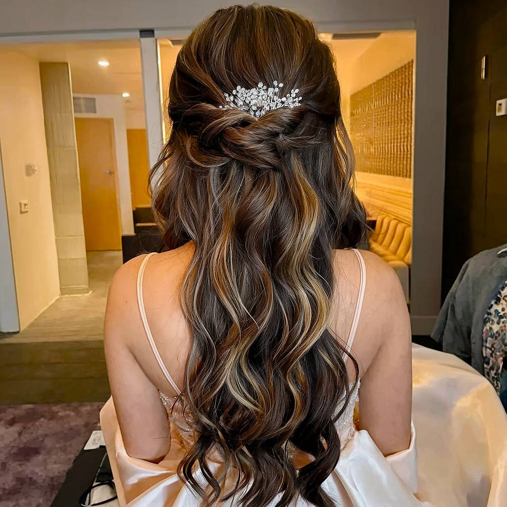 Half up half down prom hairstyle with soft curls and crystal clip