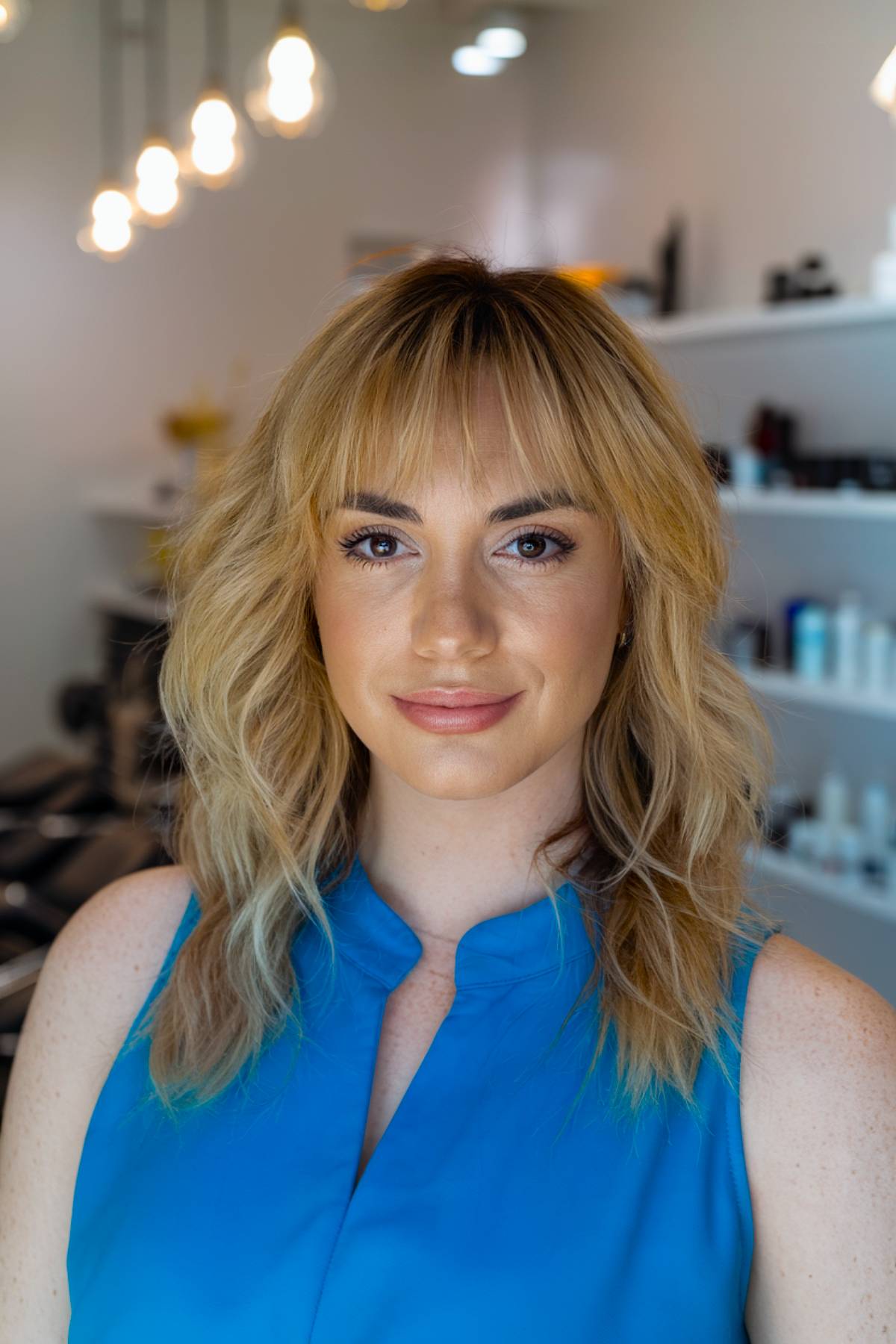 Soft honey blonde waves with airy, tousled bangs for a natural and effortless look