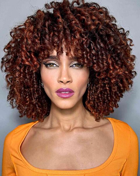 A Hydrated Curls with Red Balayage hair color at shoulder-length with bangs