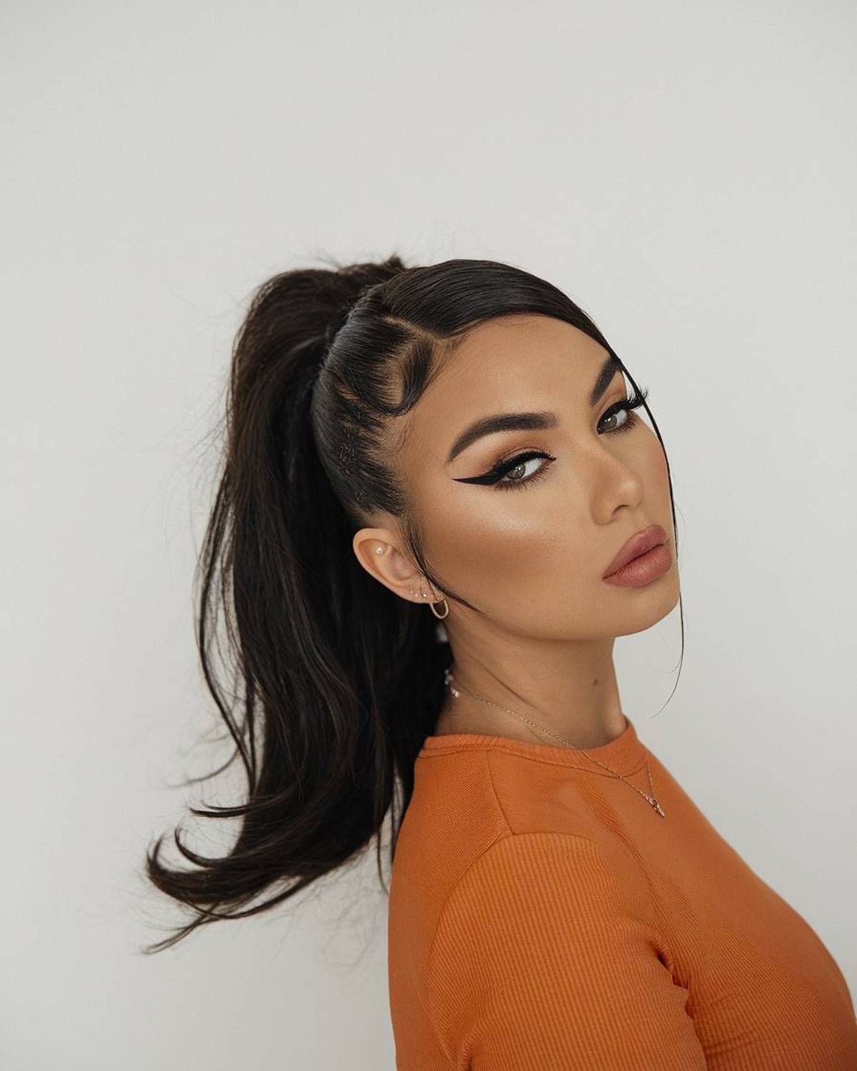 High Latina ponytail with sleek edges and face-framing strands, creating a bold and polished look