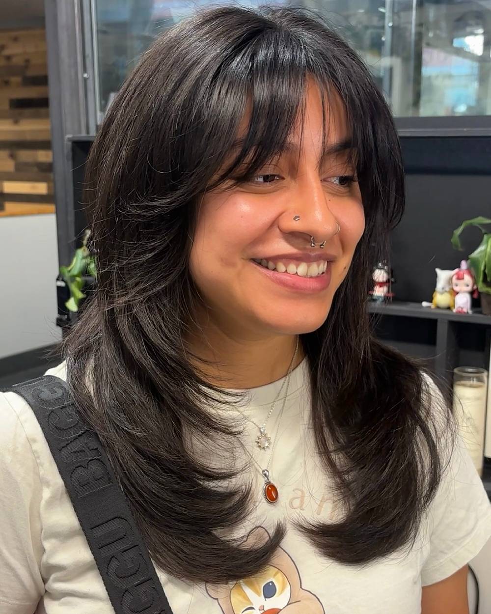 Layered haircut with feathered bangs and flipped-out ends for thick, dark medium-length hair