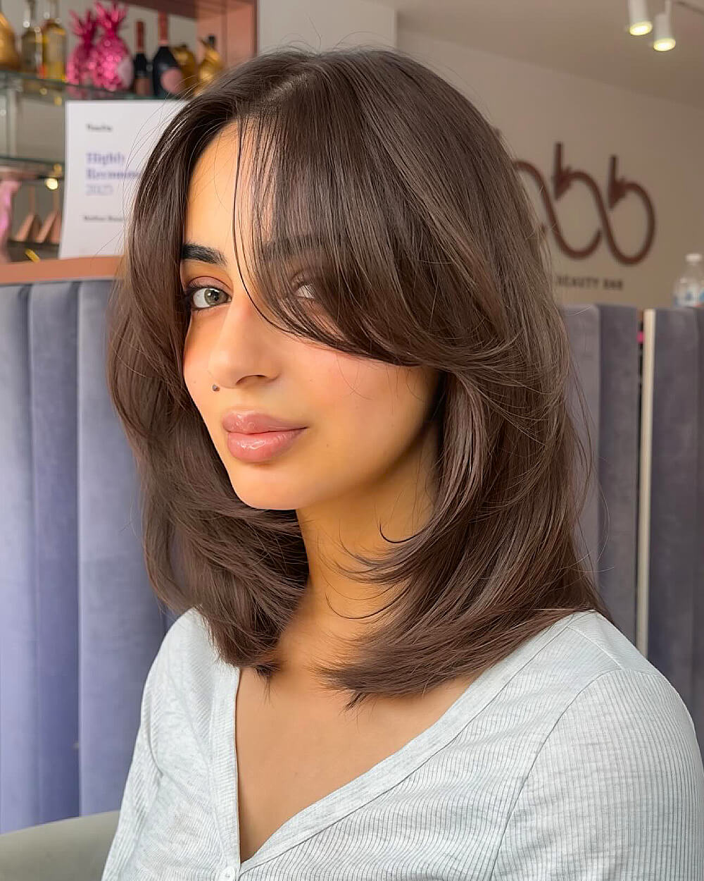 Layered medium length haircut with curtain bangs on straight hair for added volume and face framing