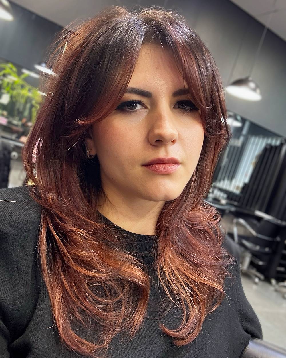 Layered medium cut with curtain bangs styled with soft face-framing layers and feathered ends for movement