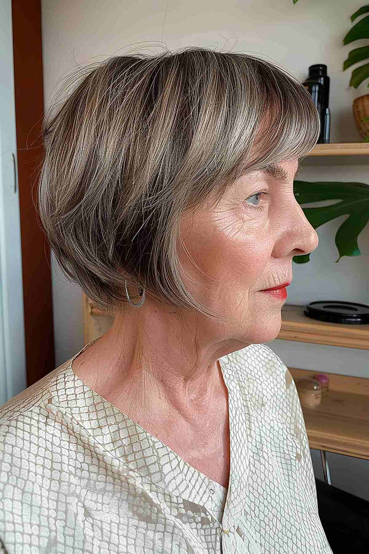 Layered pixie bob with soft bangs and natural grey highlights for older women