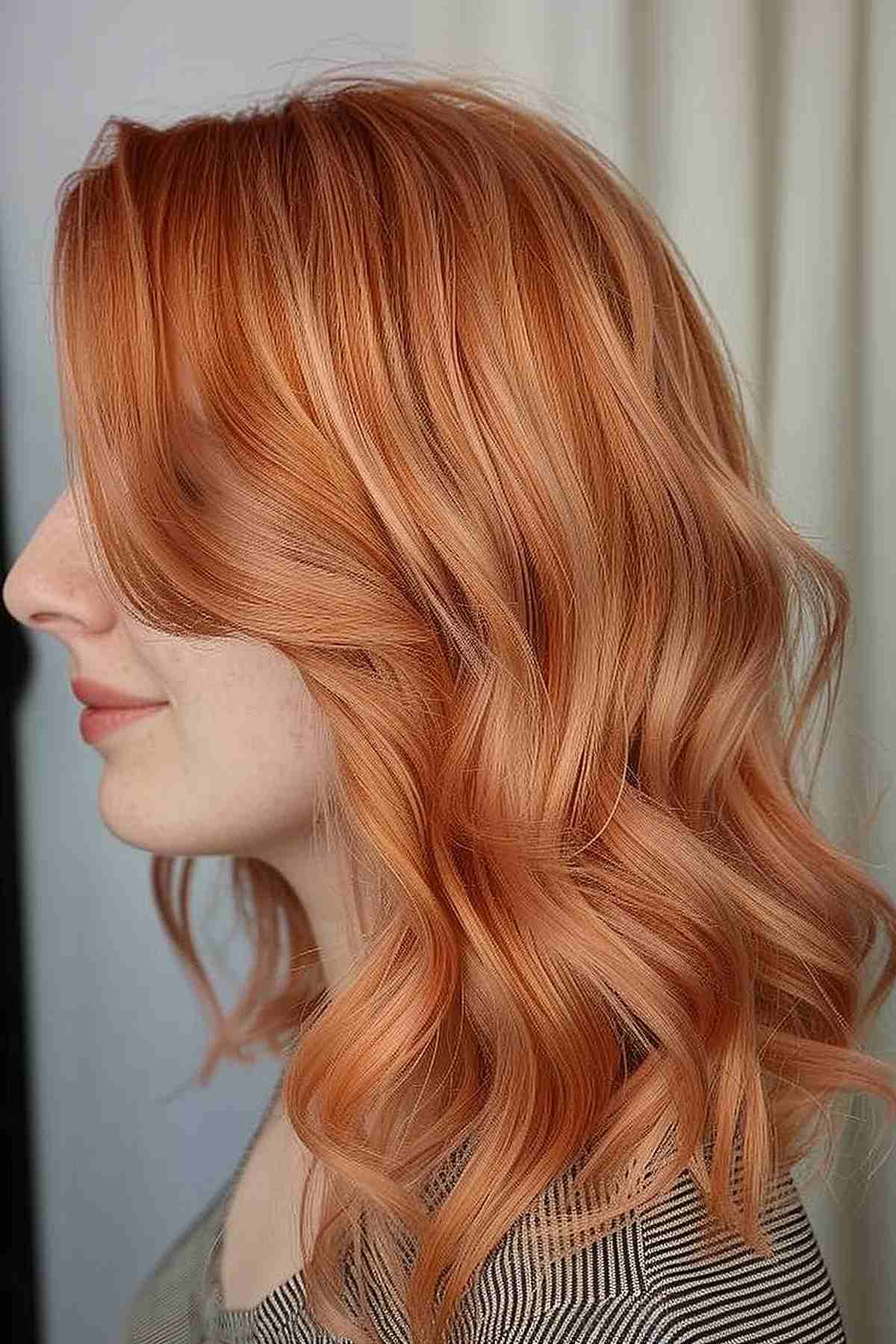 Light auburn peach tinted hair styled into soft waves, enhancing the texture and providing a warm, vibrant look suitable for fair to medium skin tones. 