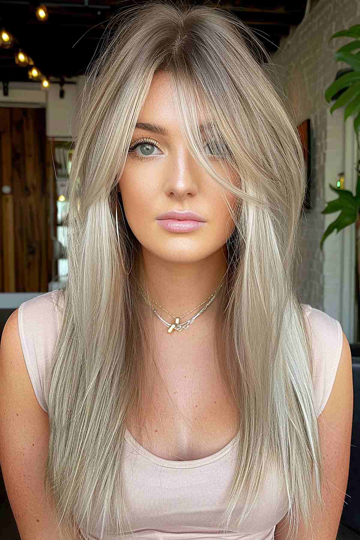 Woman with long hair featuring light layers and bangs, styled for a chic look.