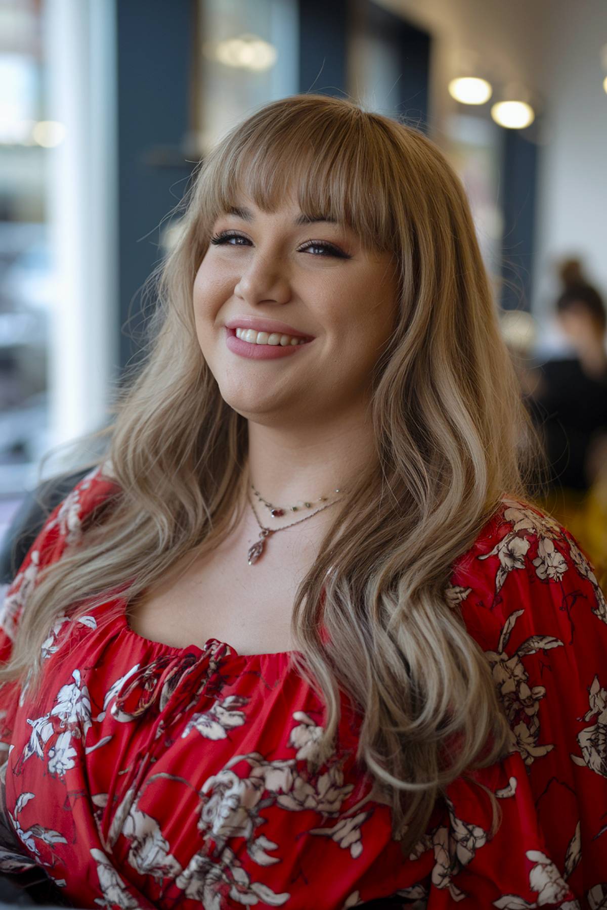 Flowy long blonde hair with full bangs designed to flatter round face shapes