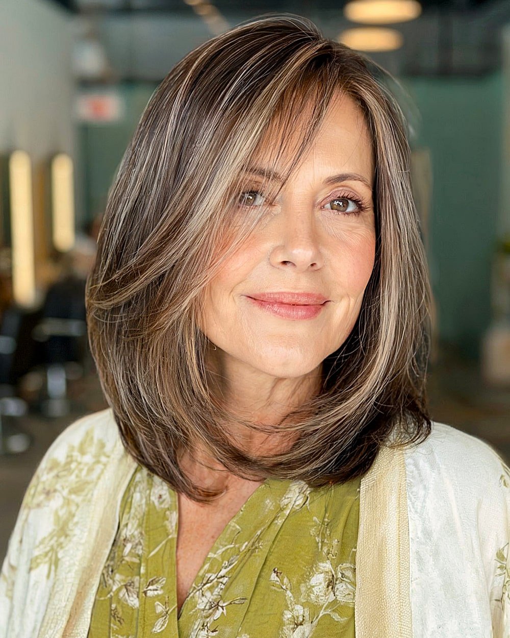 Side swept long bob with dimensional highlights for mature women over 50 seeking lift and contrast
