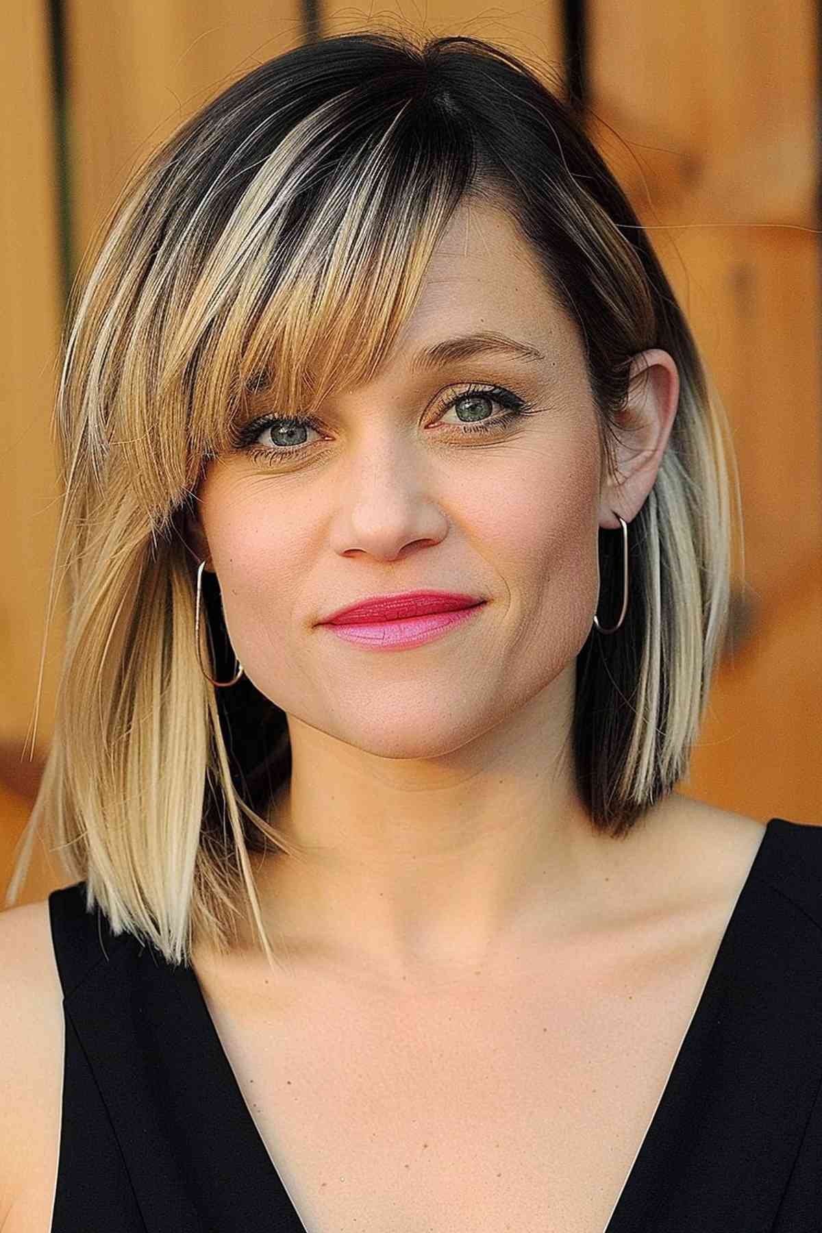 Woman with a stylish long bob featuring asymmetric bangs and blonde and brown highlights, suitable for enhancing medium to thick hair.