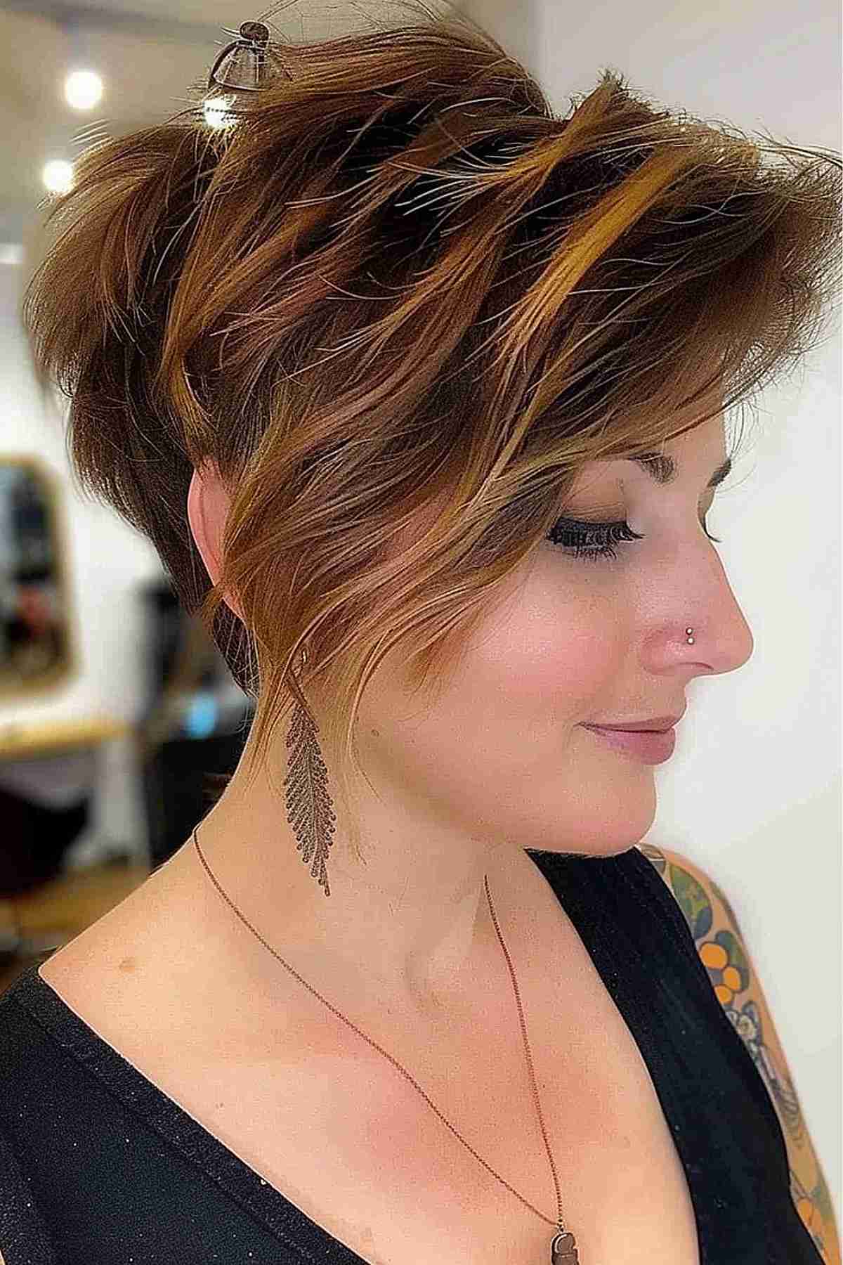 Woman with a long choppy pixie bob featuring caramel highlights, styled in textured layers suitable for medium to thick hair.