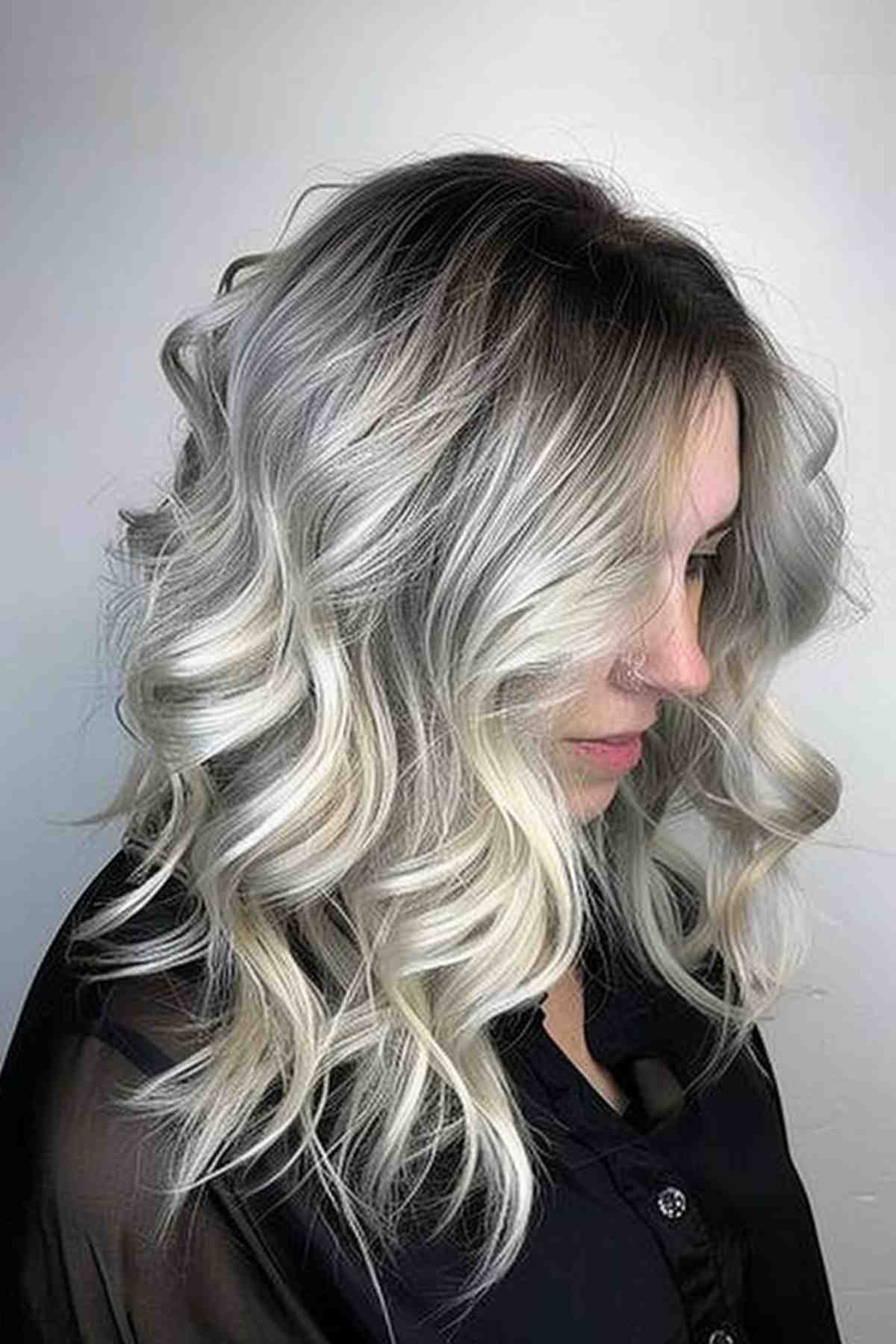 Long ombre hairstyle transitioning from dark roots to smoky grey and ending in luscious platinum blonde curls