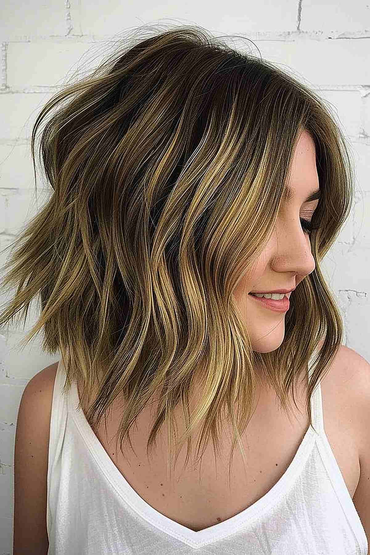 Woman with a long inverted choppy bob with caramel highlights