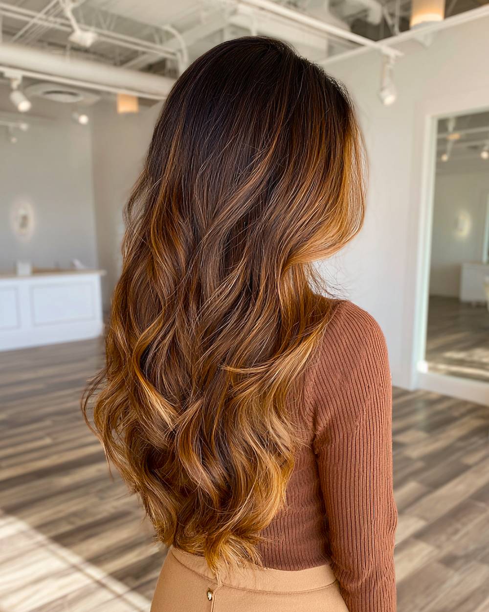 Long layered waves with dark caramel balayage on brunette hair, adding dimension and warmth to a flowing, voluminous style