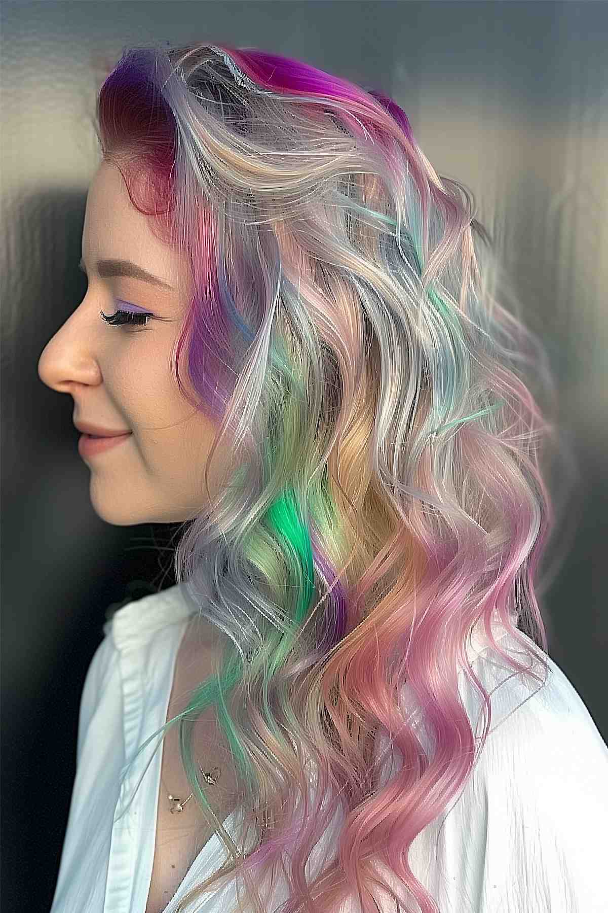 Opalescent rainbow tones in long hair styled with a half-up ponytail, featuring a transition to cool platinum ends