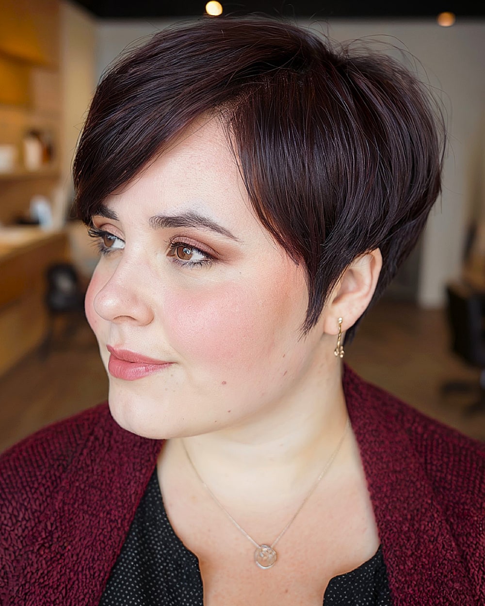 Tapered long pixie haircut with deep side part and volume on top for round face shapes