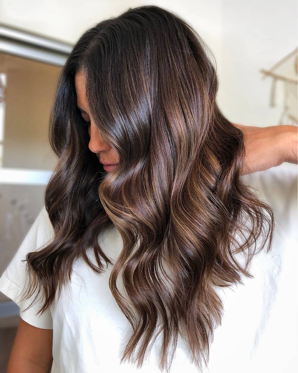 Long wavy layered hair with chocolate brown balayage highlights adding depth and shine