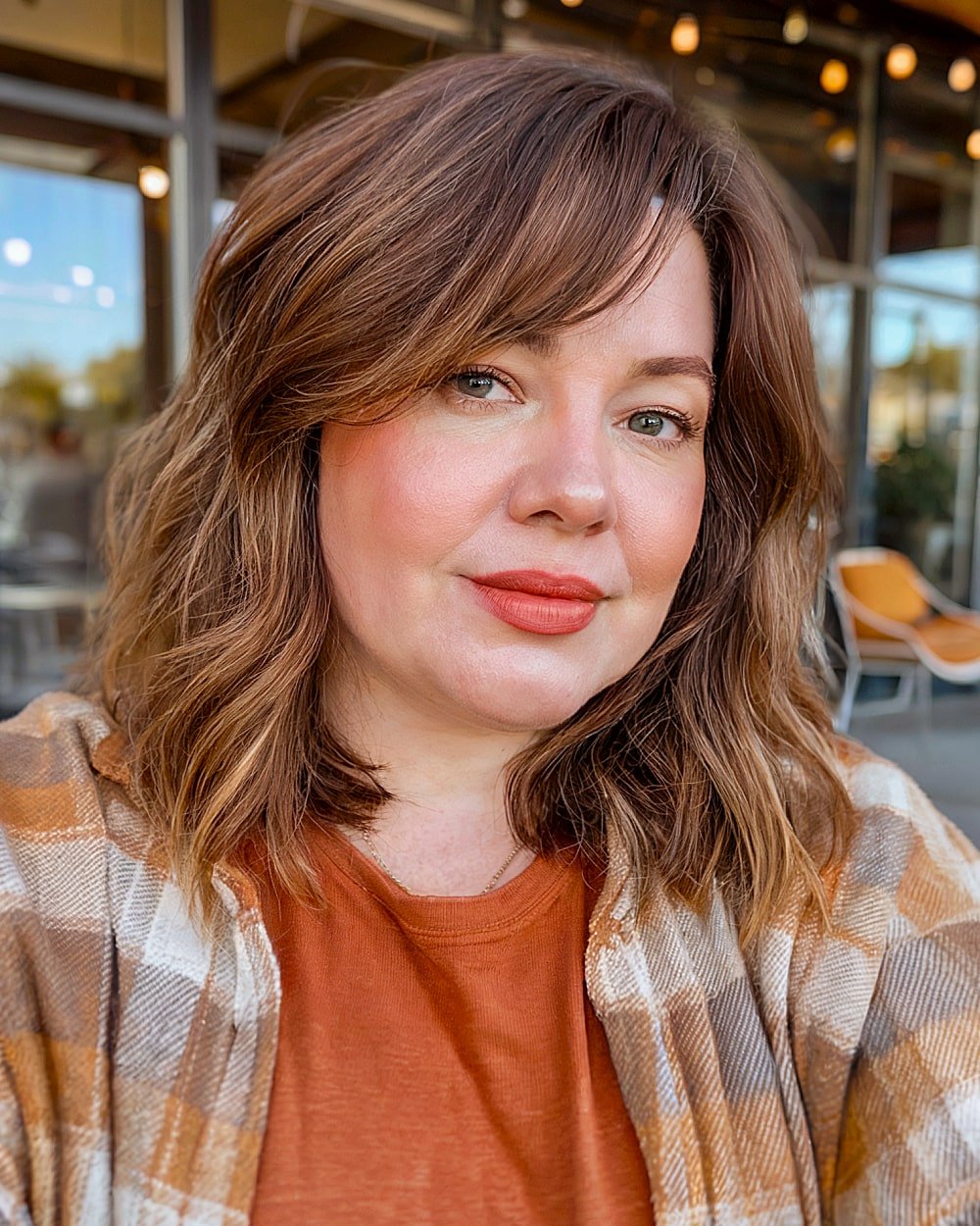 Medium choppy hairstyle with side part and subtle waves for women over 40 with round faces