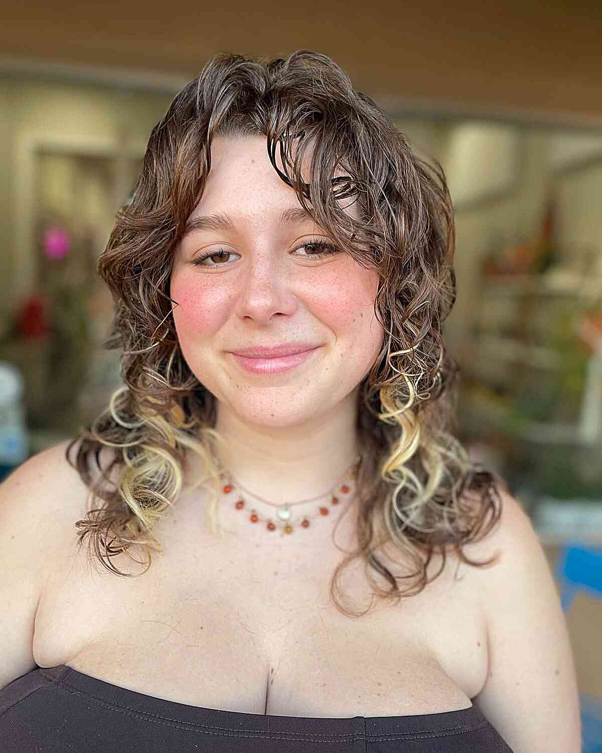 Medium Layered Hair with Loose Curly Curtain Bangs and Blonde Highlights