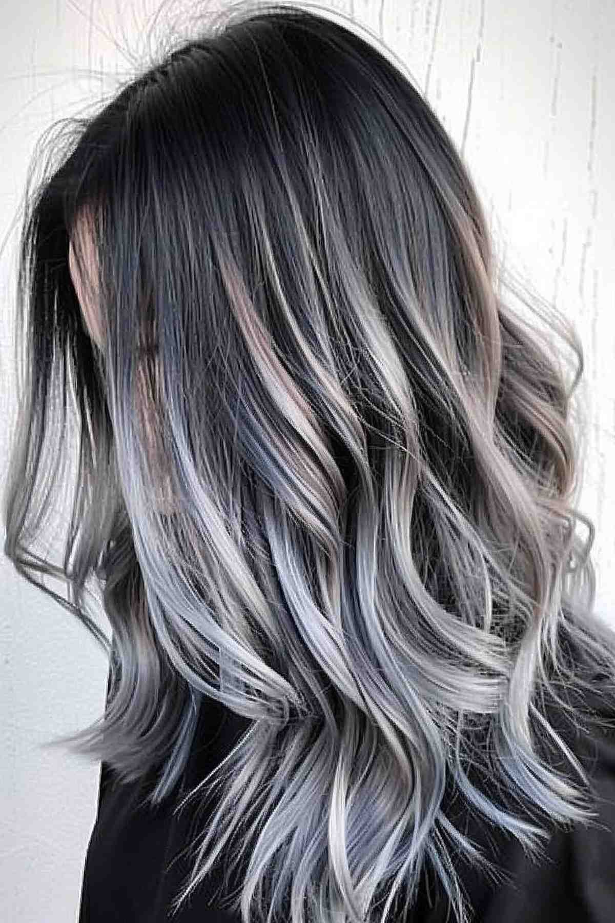 Medium-length wavy hair transitioning from black to grey with subtle pastel highlights.