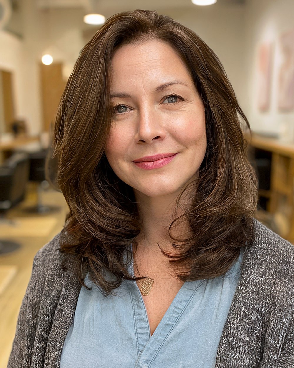 Medium layered brunette haircut with inward curled ends for round faces over 40