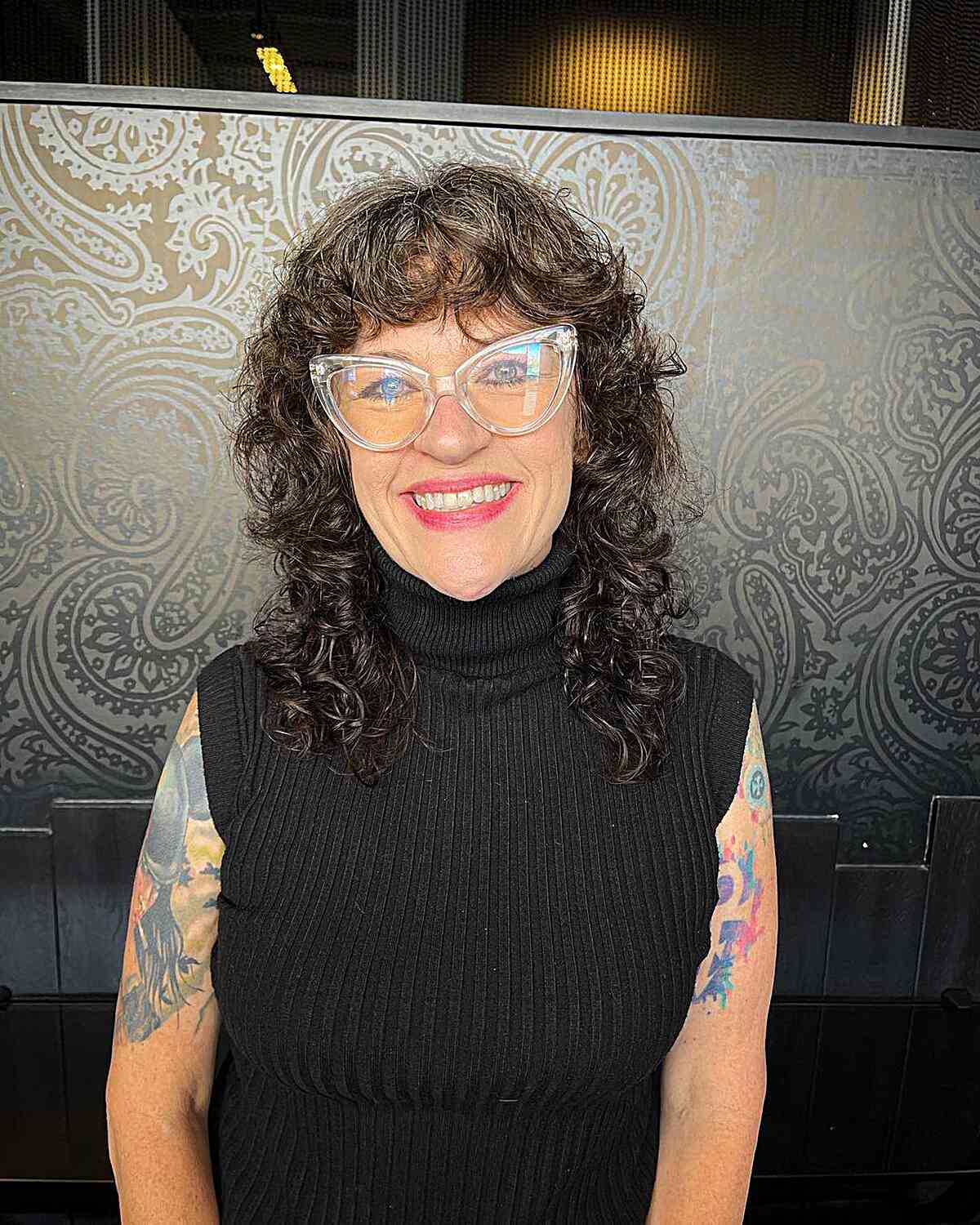 Medium-Length Curled Shag and Bangs for Women Wearing Glasses in Their Sixties