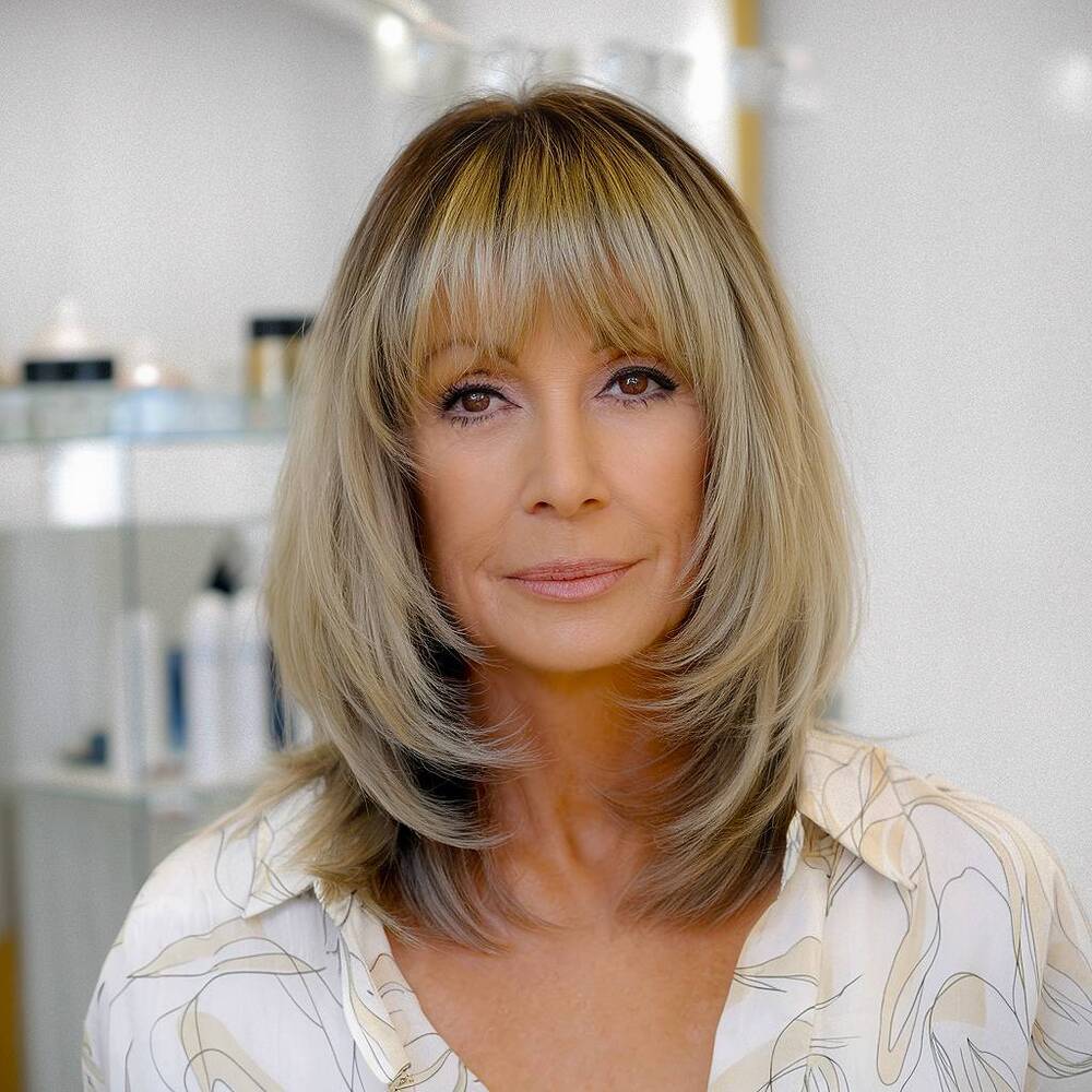 Medium-length haircut with wispy bangs, a soft and feminine look for women over 60