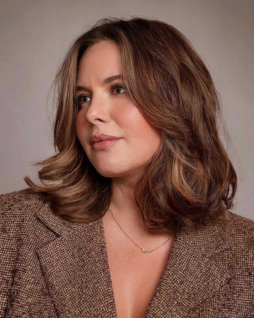 Textured medium-length haircut with curled ends and layered movement for women over 40 with round faces