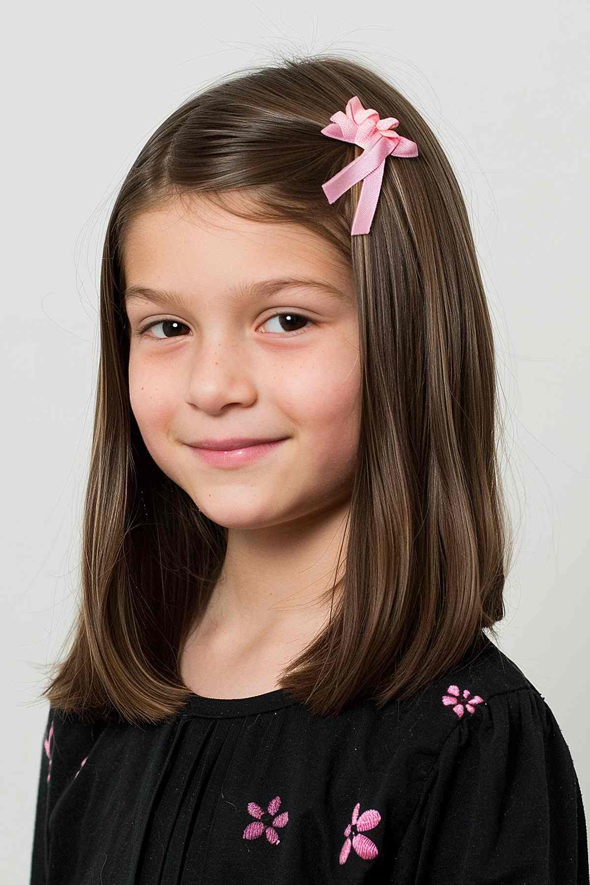 Young girl with medium straight hair and a pink bow