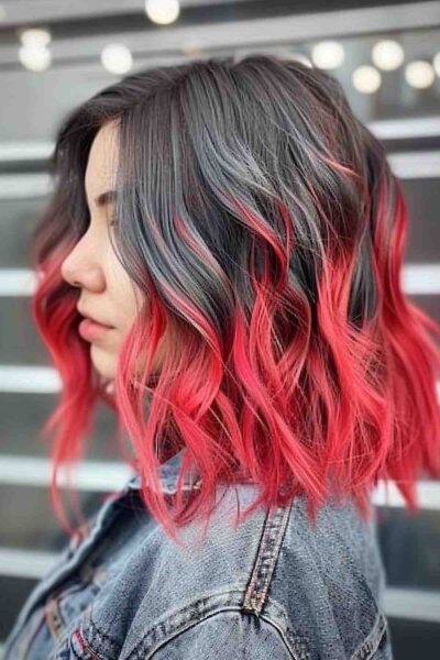 A Textured medium lob with dark roots transitioning to vibrant red ombre.