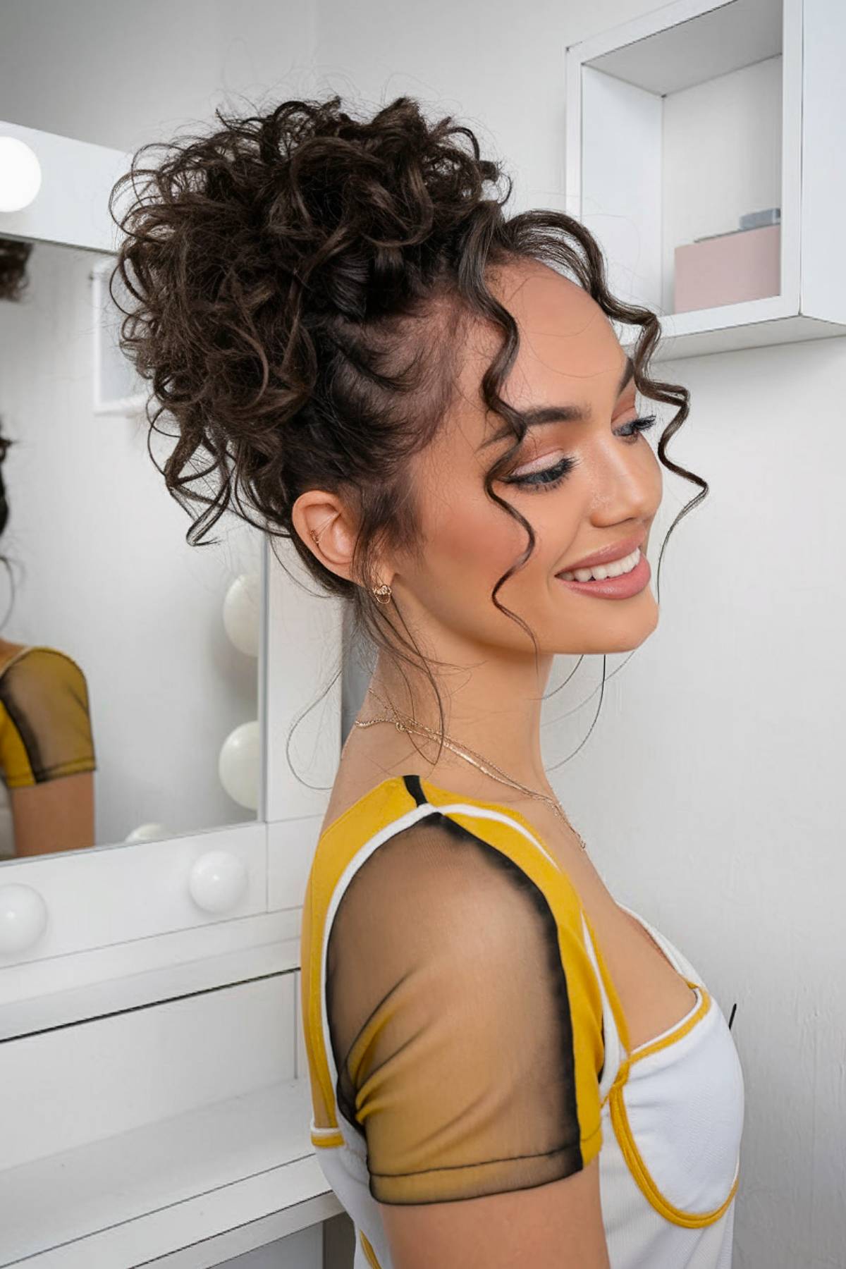 Messy curly hair bun with loose face-framing tendrils for a relaxed, natural look