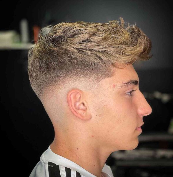 A Messy Thick Curly Hair with a Mid Fade for Teens