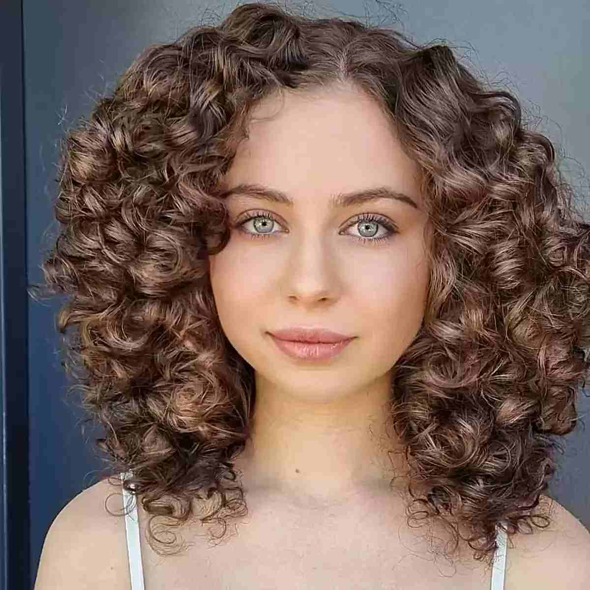 Mid-Length Thick Curly Brown Hair with an Off Center Part and Face-Framing