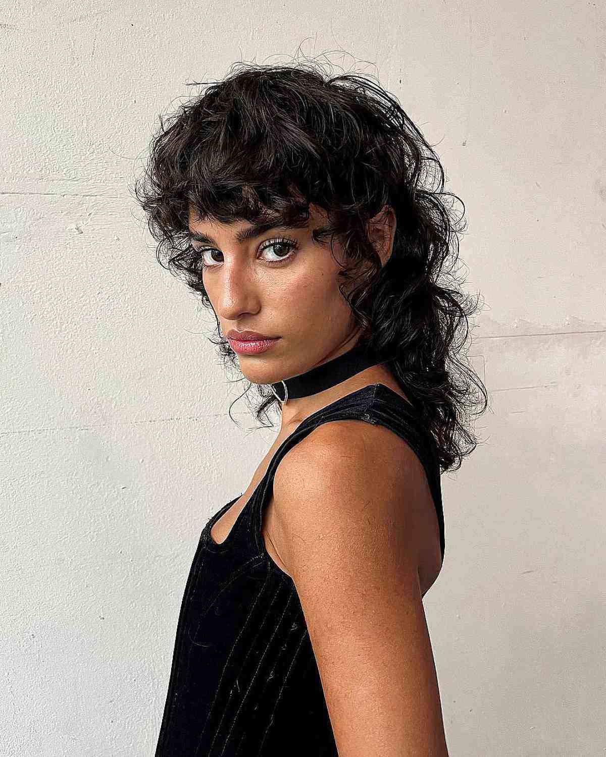 Modern curly mullet with textured bangs and layered curls on naturally curly hair